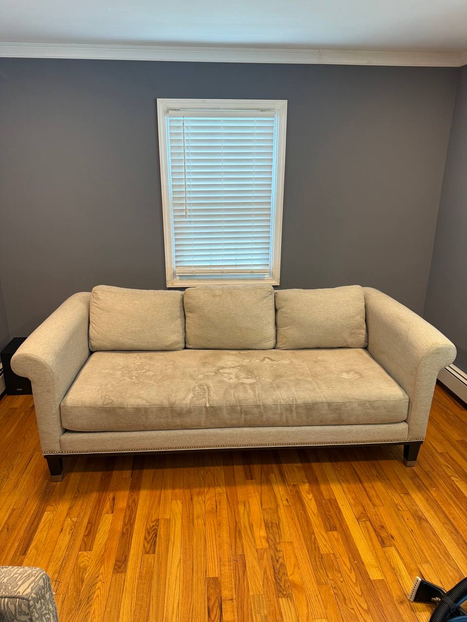Light sofa beneath a window with visible marks across the seat before cleaning
